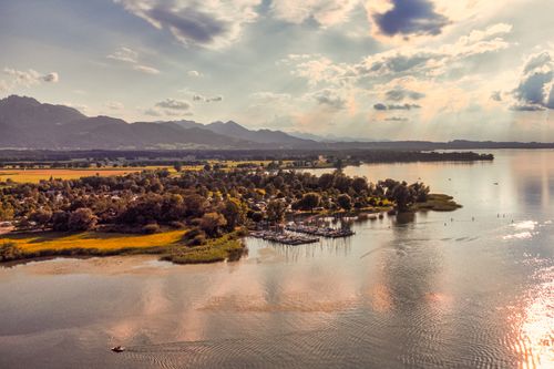Free A picturesque aerial view of a lakeside town with mountains in the background, captured at sunset. Stock Photo