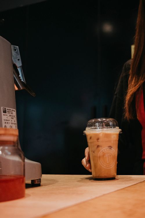Free A close-up of a barista serving an iced coffee in a modern cafe. Stock Photo
