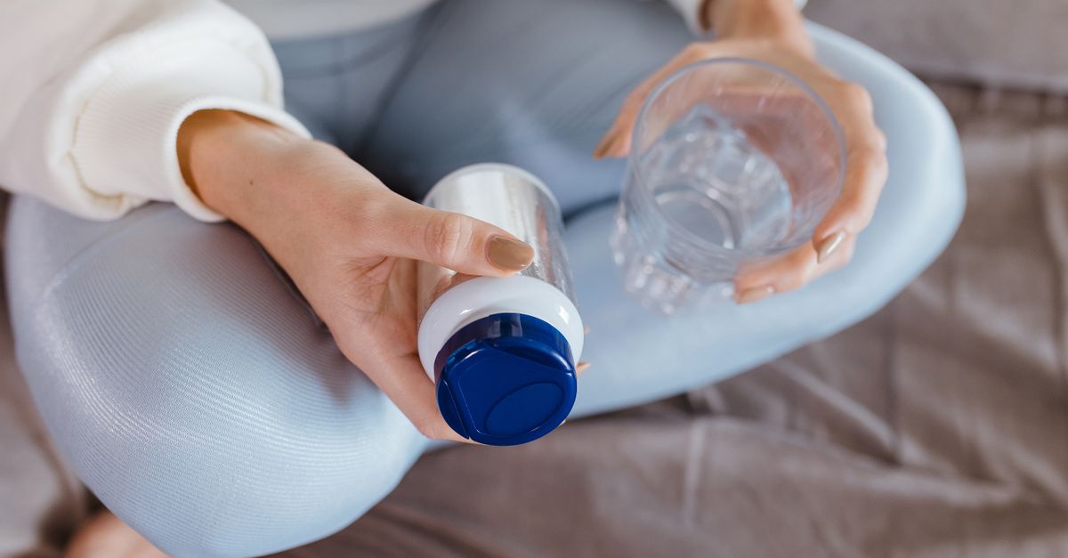 Close-up of a person's hands holding natural health supplements with a blurred background of a cozy home
