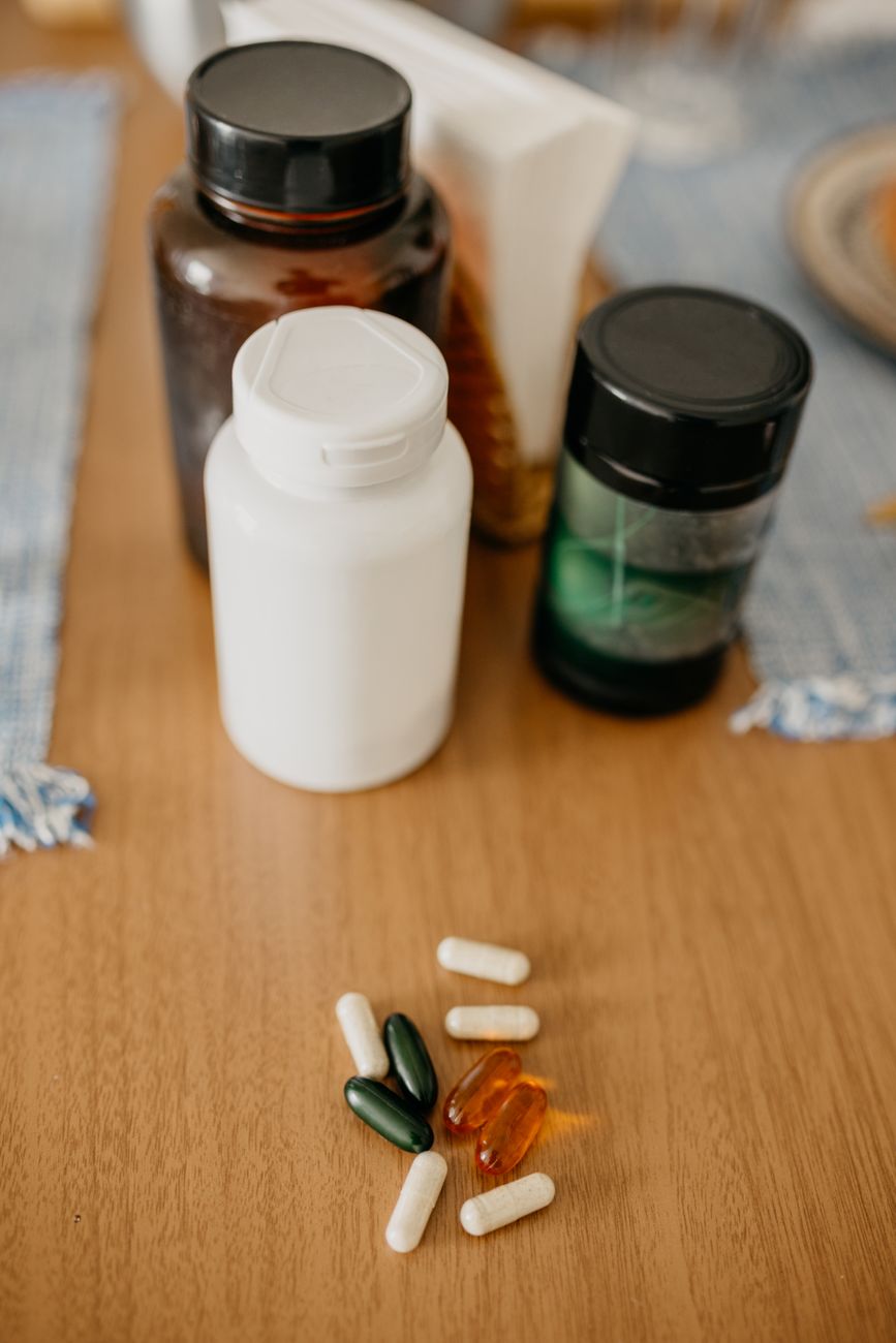 Several supplement bottles and loose capsules arranged on a wooden table.