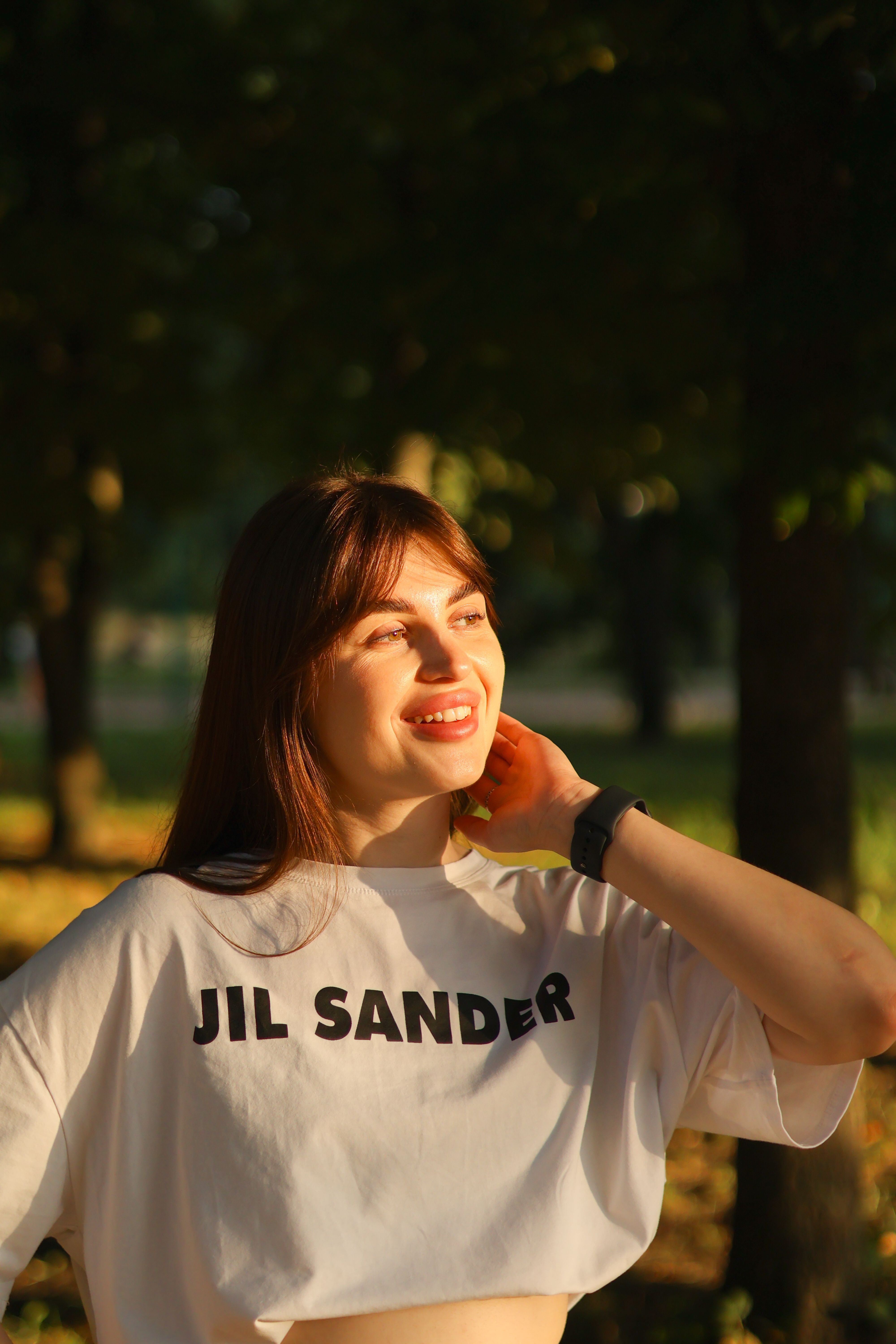 Young woman in a crop top smiling and enjoying the sunlit outdoors.