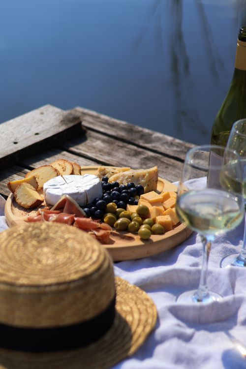 Free Elegant lakeside picnic setup with cheese, fruit, and white wine. Stock Photo