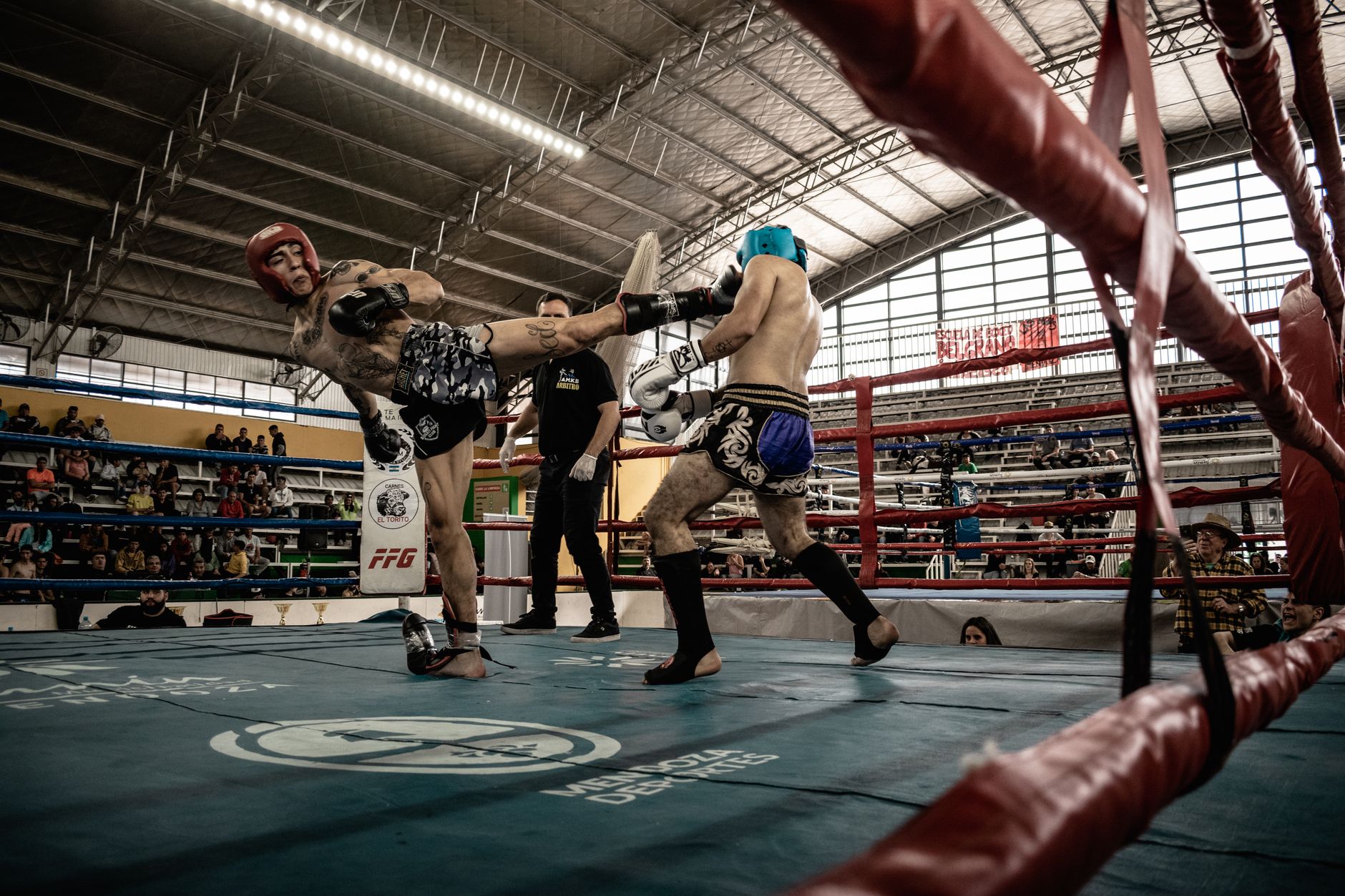 Intense action shot of a kickboxing match inside a packed arena, showcasing athleticism and skill.