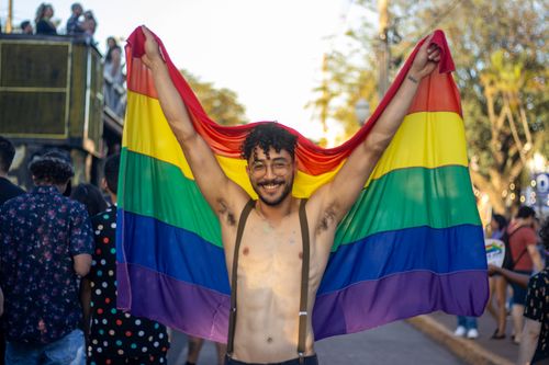 Free Smiling man holding a rainbow flag at a lively pride parade outdoors. Stock Photo