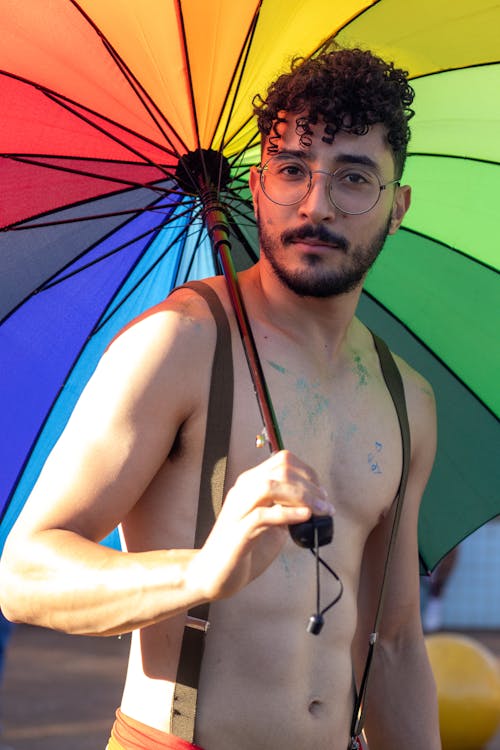 Young Shirtless Man Holding a Colorful Umbrella 
