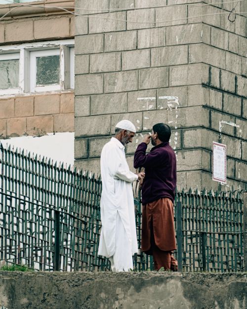 Free Two men converse near a fence by a building in Srinagar, India. Stock Photo