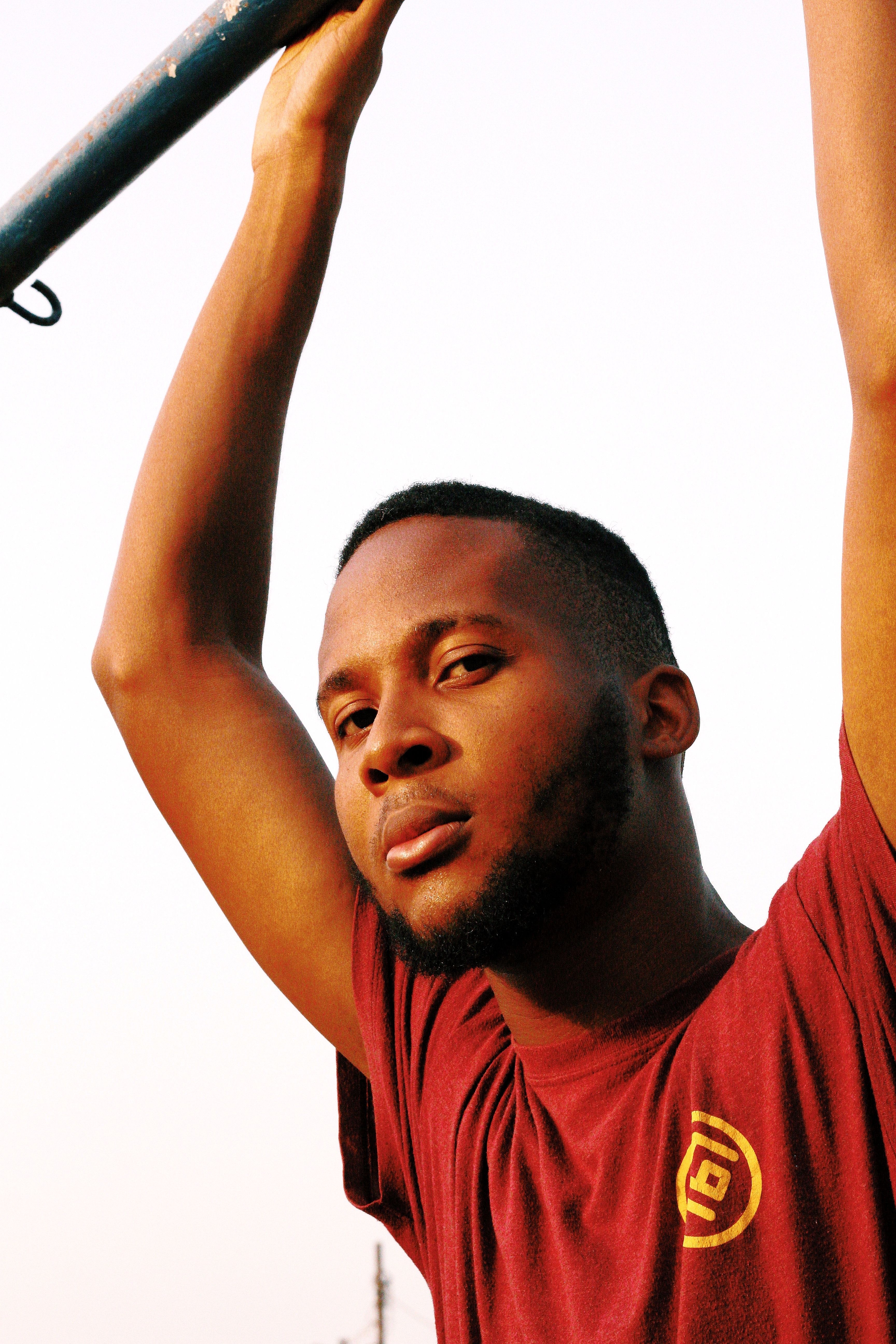 Strong portrait of a young man in Abuja with arms raised, showcasing confidence.