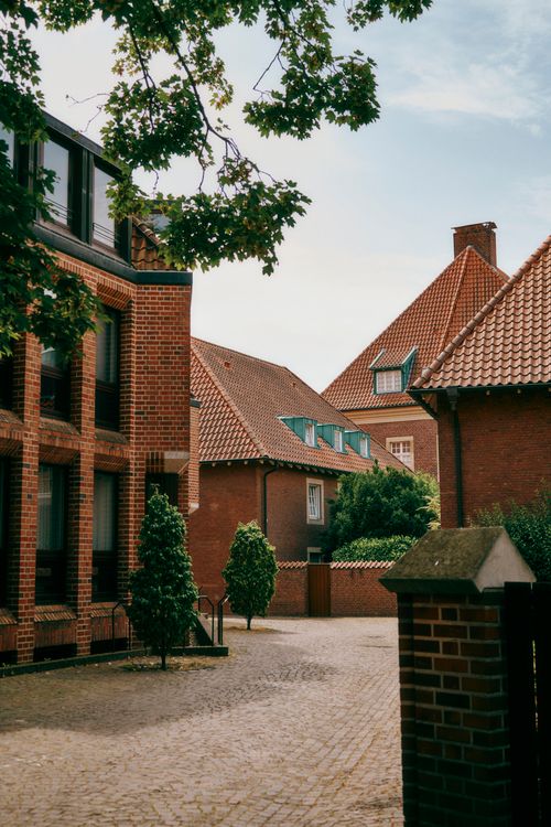Free Picturesque brick houses with tiled roofs and a peaceful courtyard surrounded by greenery on a sunny day. Stock Photo