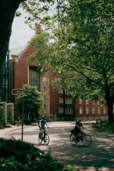 Cyclists enjoying a sunny day on city streets with brick buildings in Münster, Germany.