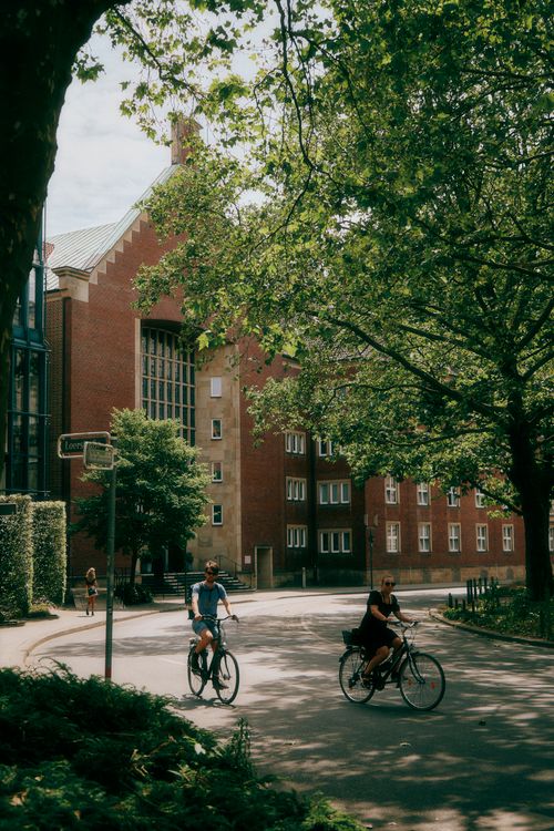 Free Cyclists enjoying a sunny day on city streets with brick buildings in Münster, Germany. Stock Photo