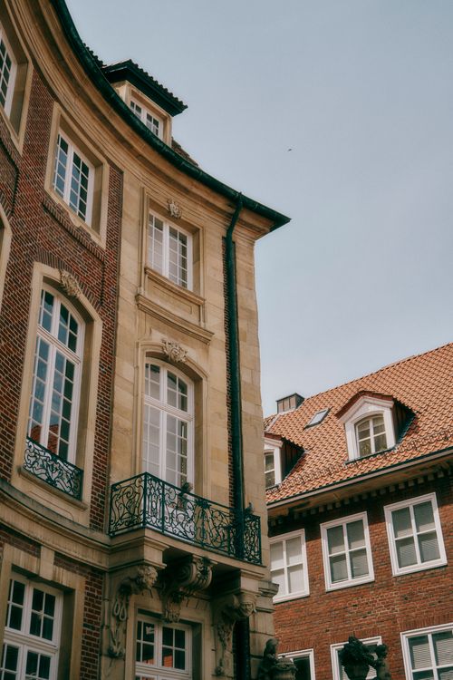 Free Elegant urban scene with historic brick buildings and decorative balconies under a blue sky. Stock Photo