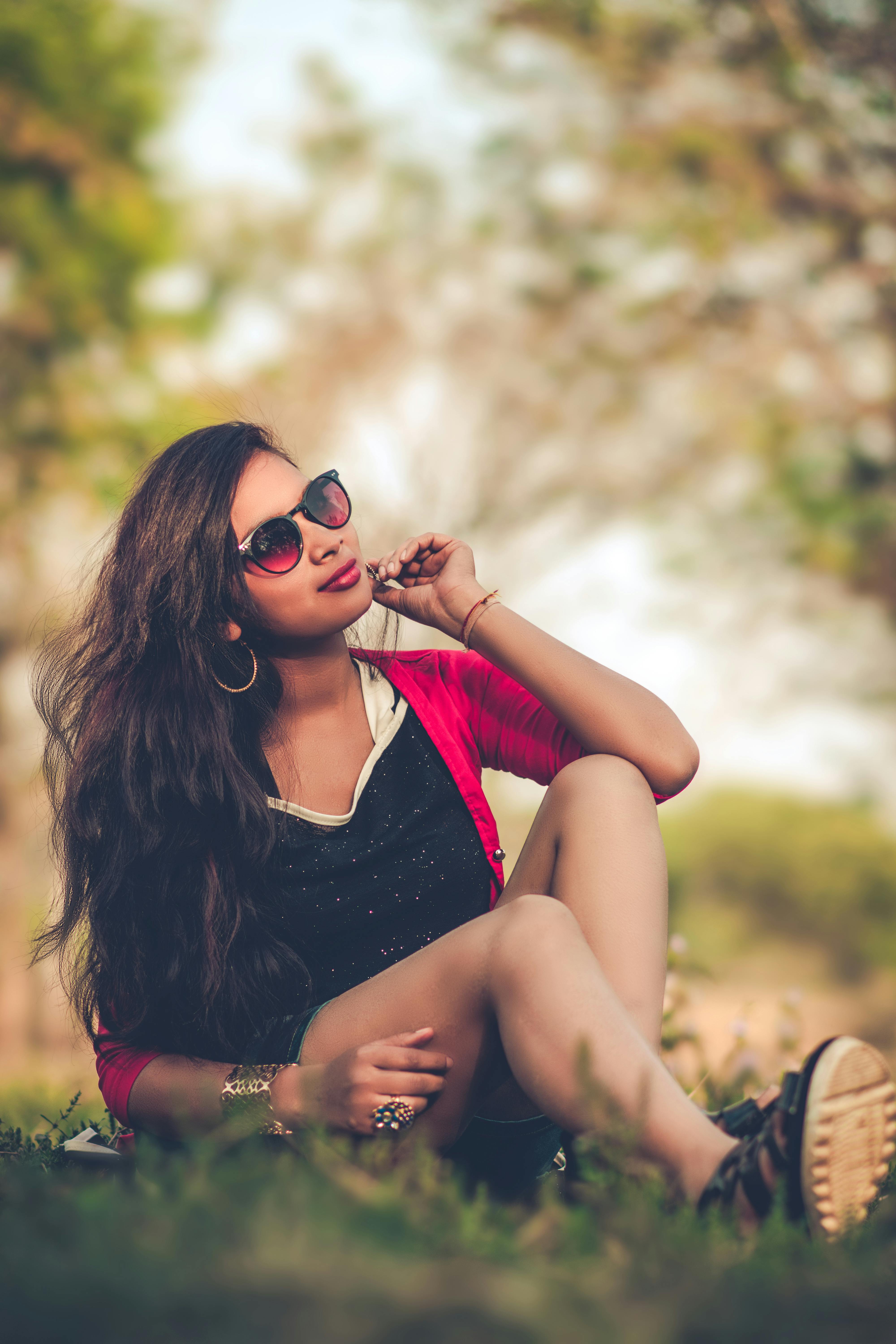 一位戴着太阳镜的年轻女子坐在户外，散发着自信和现代时尚风格