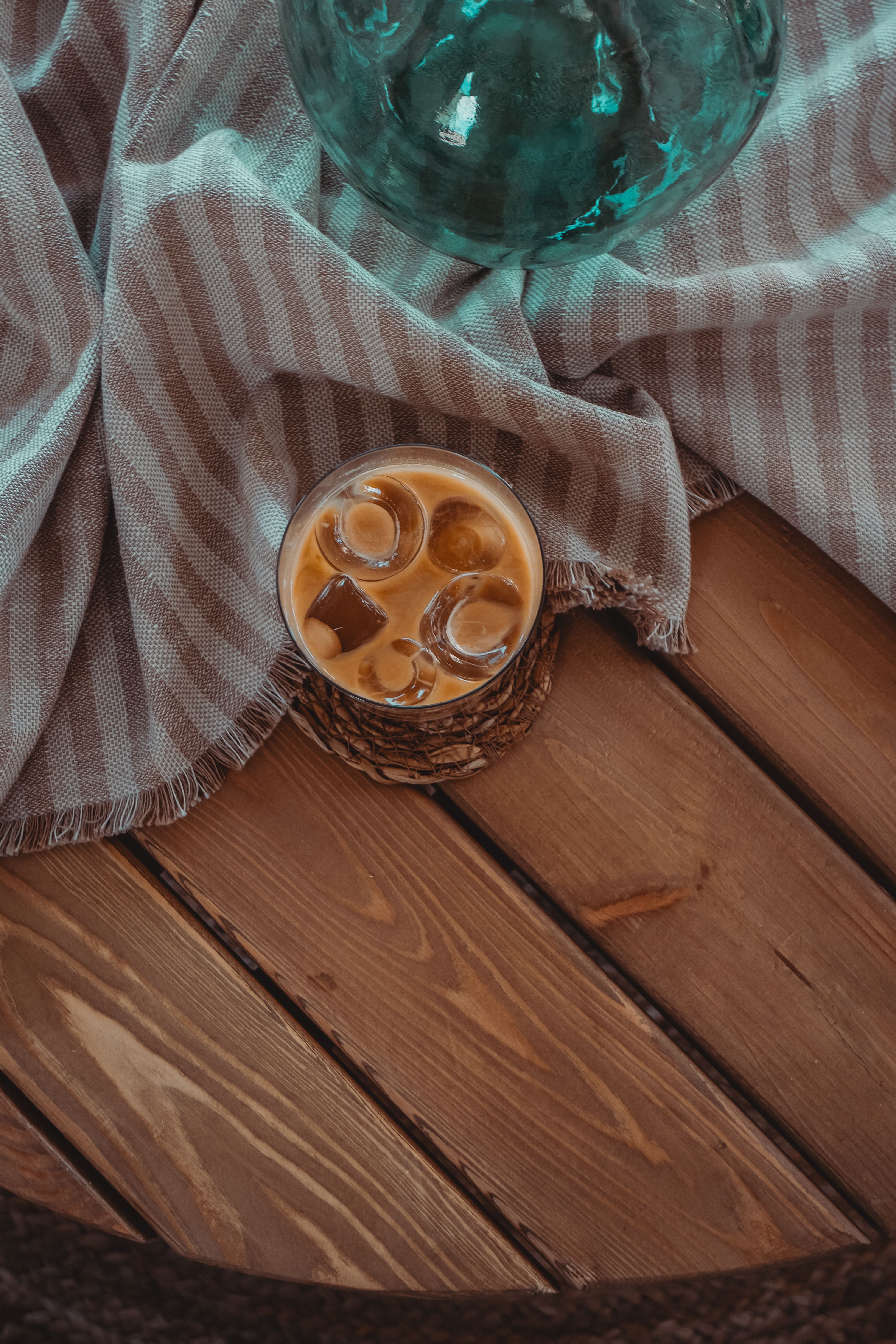 Top view of a refreshing iced coffee on a rustic wooden table with a striped fabric background.