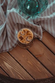Top view of a refreshing iced coffee on a rustic wooden table with a striped fabric background.