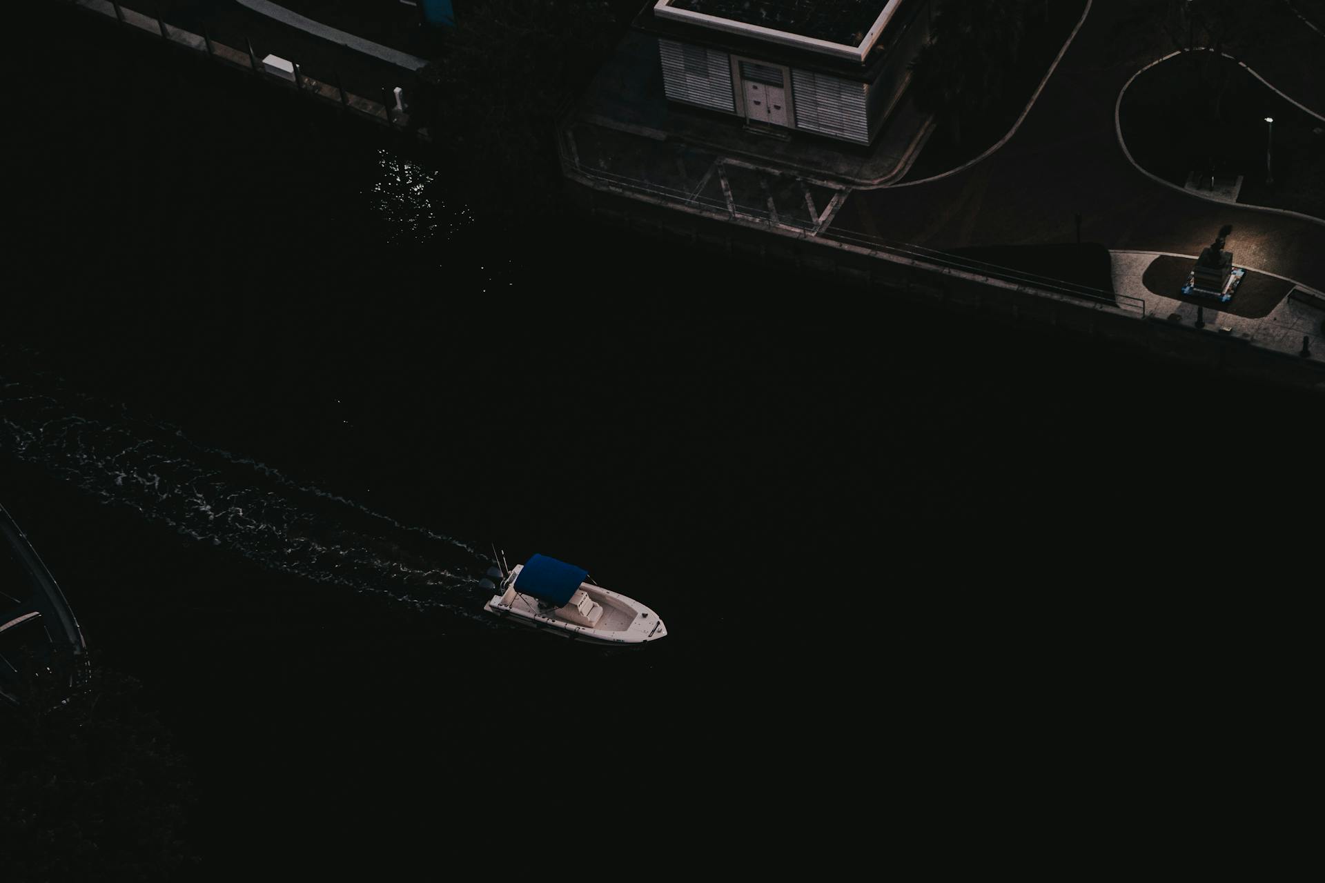 Aerial shot of a small boat traversing dark waters near Fort Lauderdale, Florida at night.