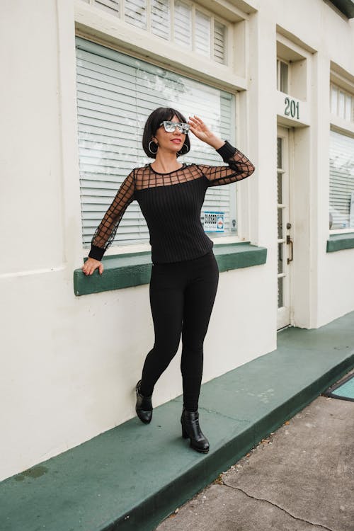 Woman in Black Clothes Posing by Building Window