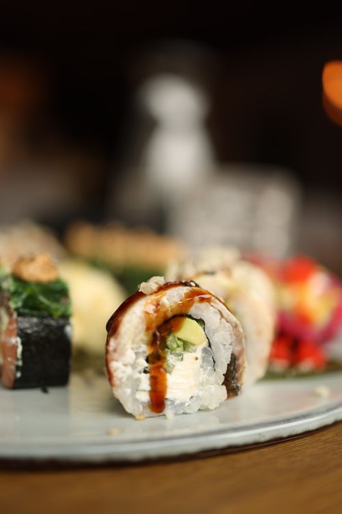 Free Mouth-watering sushi roll with avocado, focus on intricate details and sauces. Stock Photo
