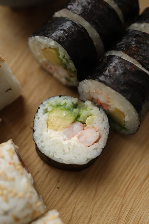 Free Close-up image of fresh sushi rolls with shrimp and avocado on a wooden surface. Stock Photo