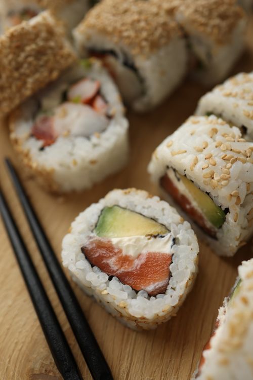 Free Appetizing sushi rolls with fish and avocado on a wooden board. Perfect for food lovers. Stock Photo