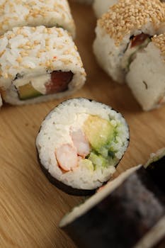Close-up of sushi rolls featuring fresh avocado and seafood on a wooden board.
