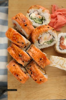 A vibrant top view of assorted salmon sushi rolls on a wooden board.
