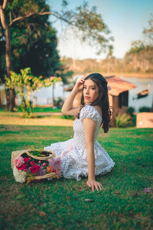 Young Woman Sitting on the Lawn with a Bunch of Flowers next to her 