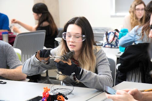 Student in Goggles Sitting by Table in Classroom