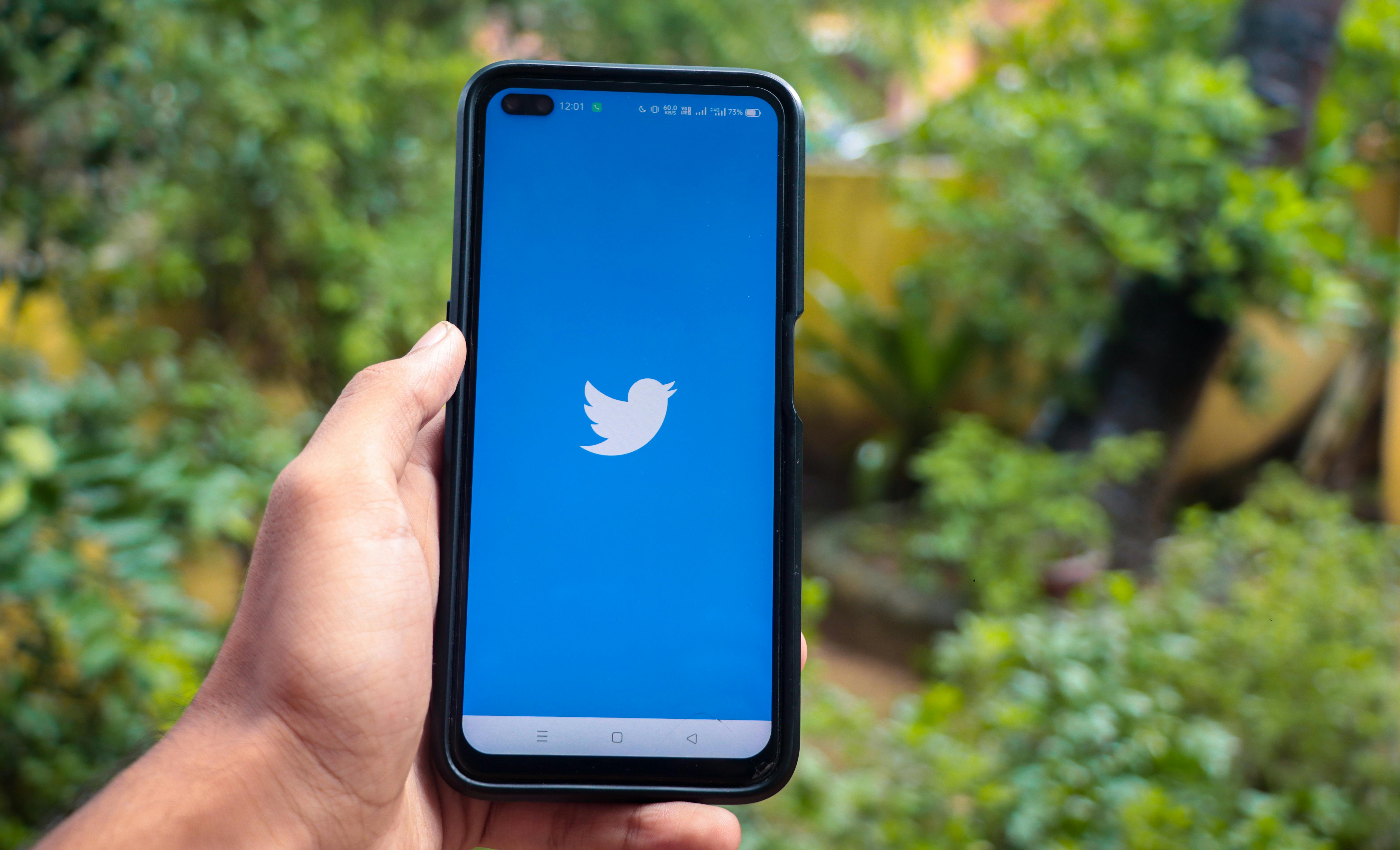 hand holding a smartphone with twitter icon on screen iphone with a social media app logo