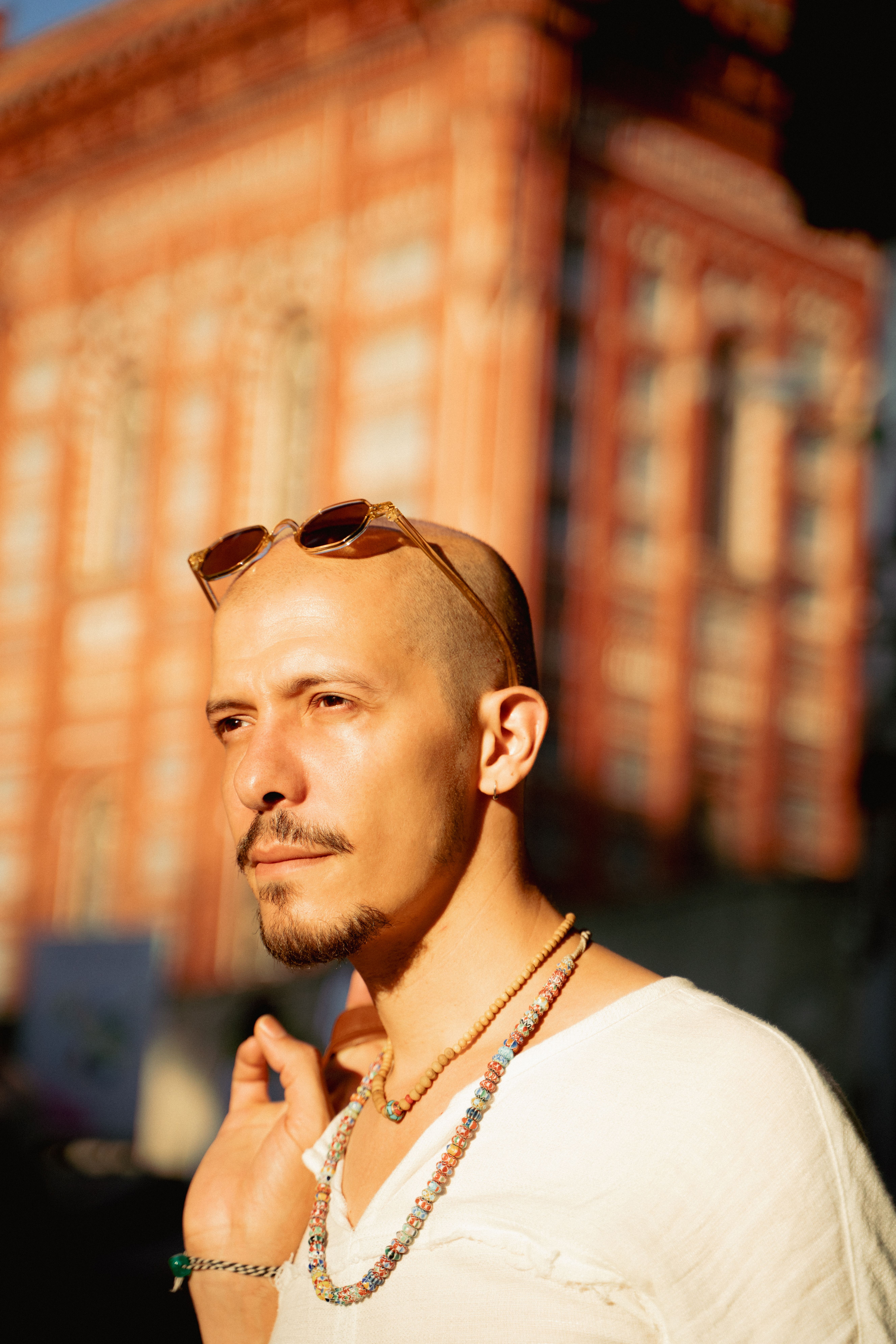 Bald man wearing sunglasses and necklaces in front of a historic building in Istanbul.