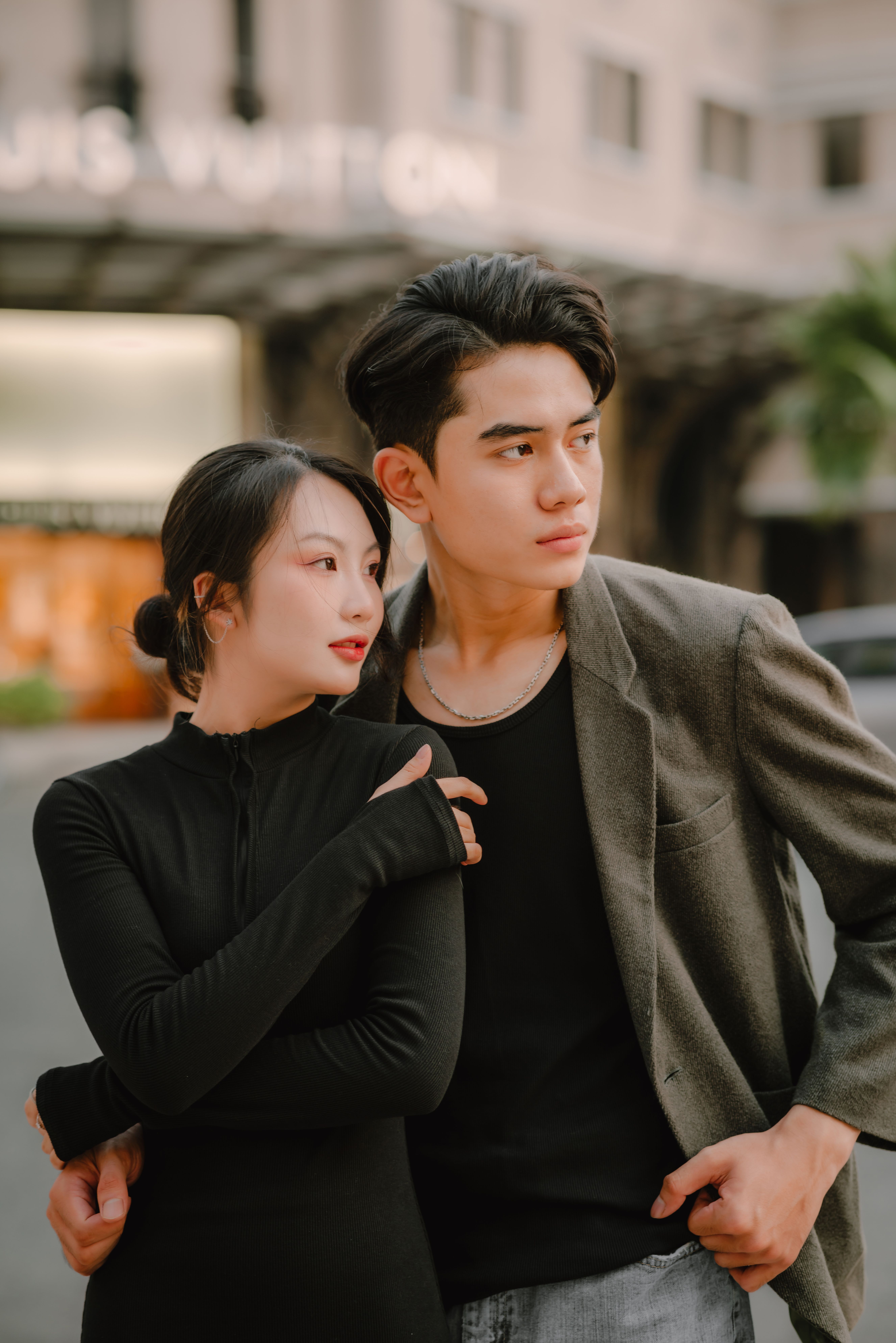 A young couple poses stylishly outdoors, showcasing affection and elegance at sunset.