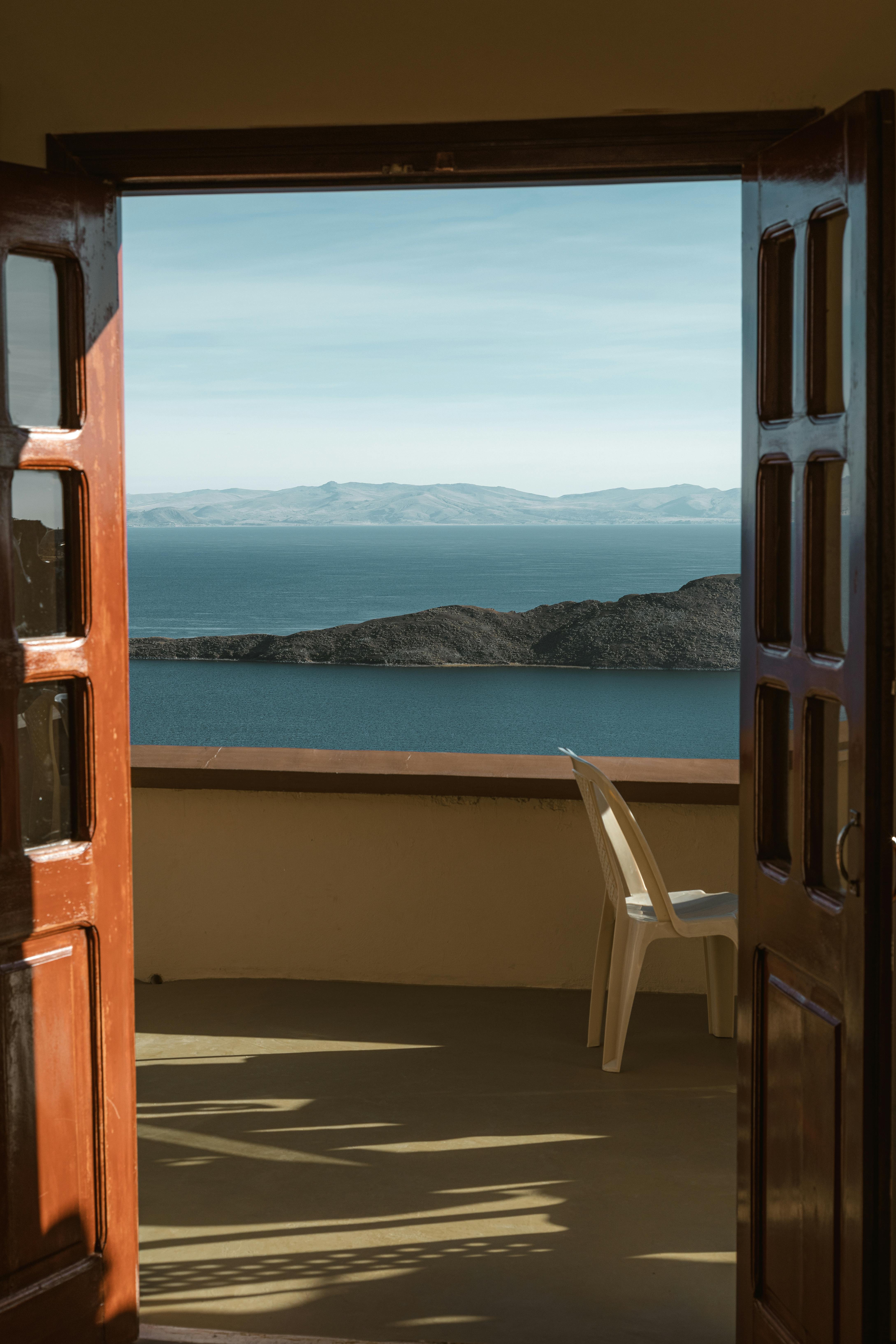 Open doors leading to a balcony with sea and island view.