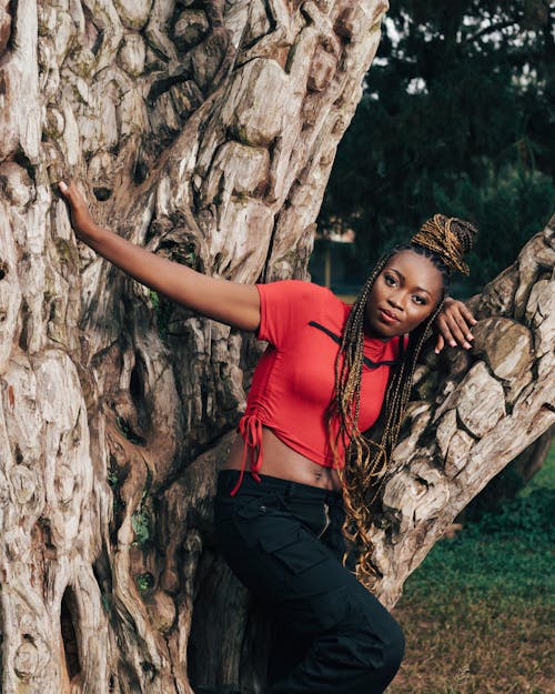 Portrait of a Female Model Wearing a Red Crop Top Leaning on a Tree Trunk