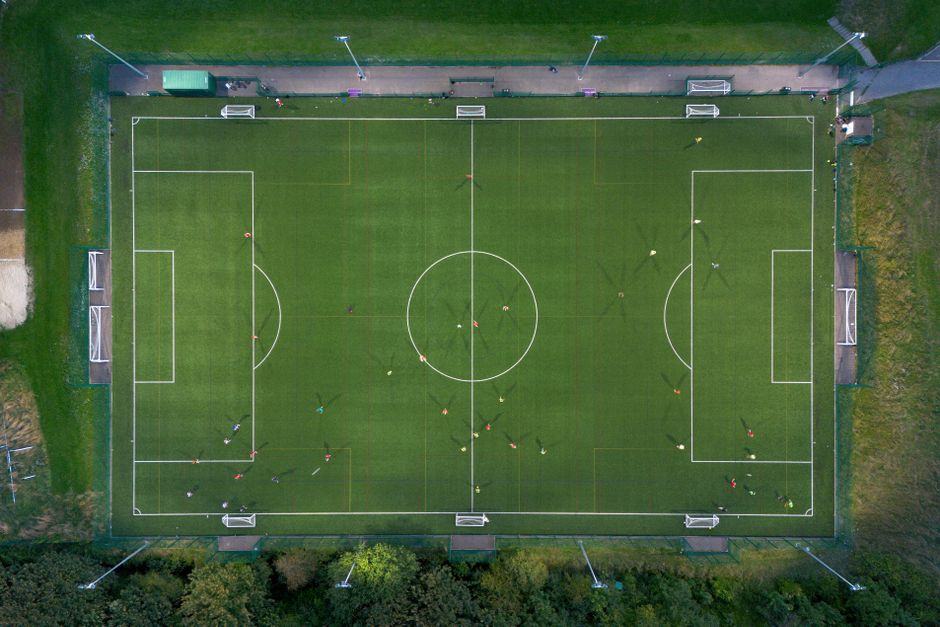 Top-down shot of a soccer match on a green field in Brighton, UK.