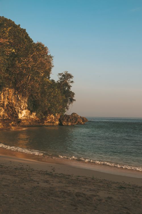 Free Tranquil beach at sunset with lush cliffs in Padang, West Sumatra. Stock Photo