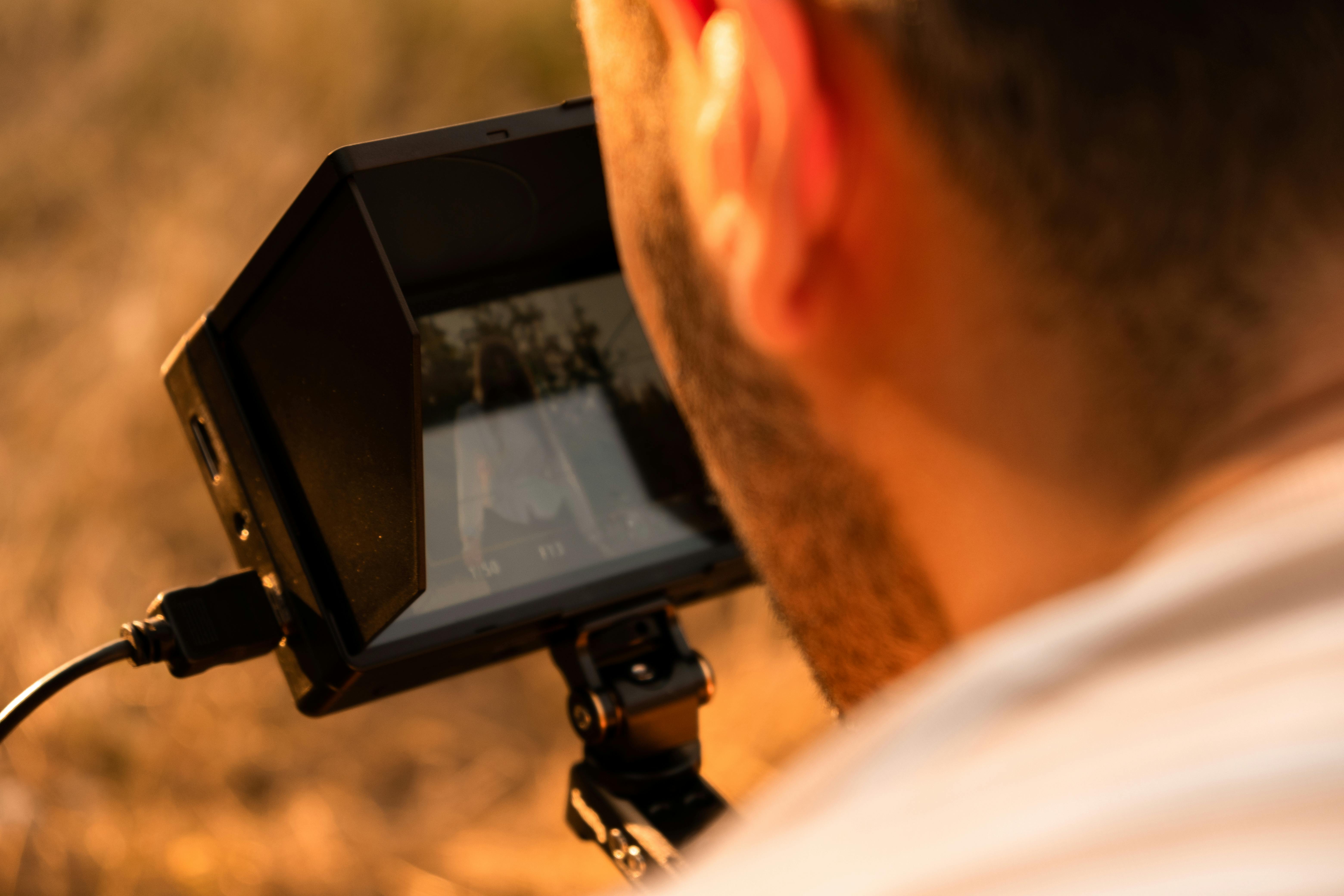 A photographer adjusts the camera screen in a warm outdoor setting.