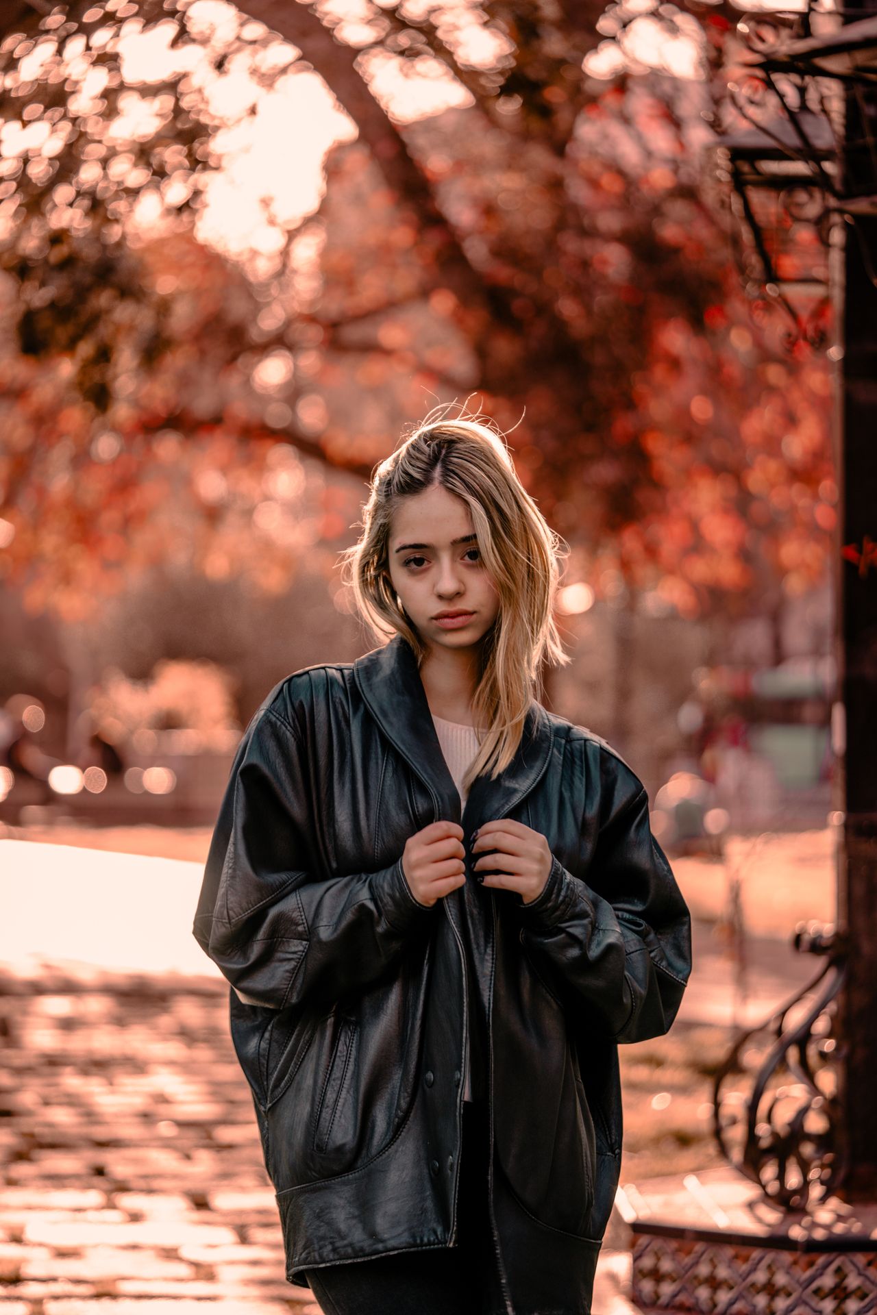 Woman in a cognac suede jacket seen from behind standing in autumn woods