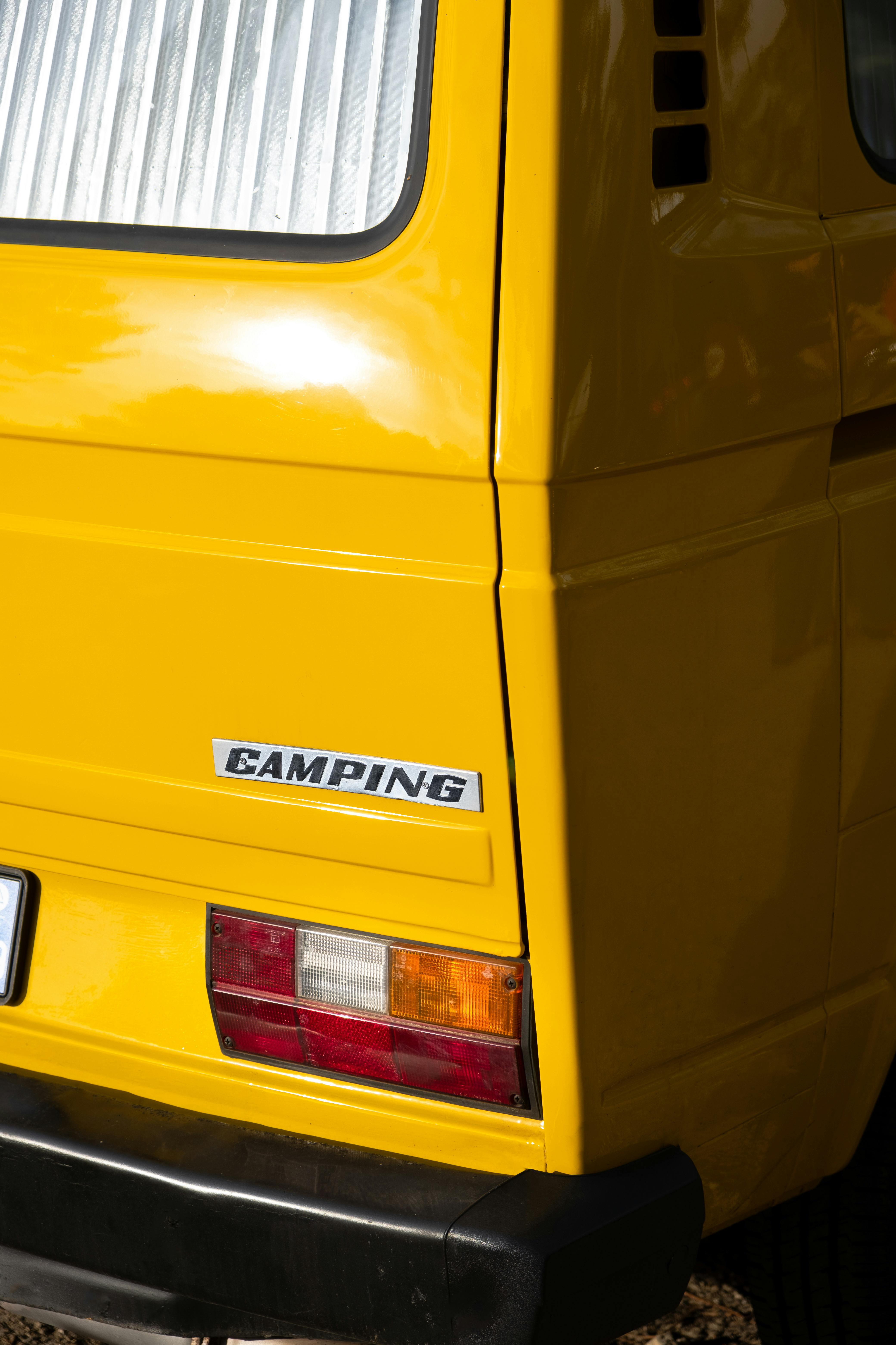 Detailed view of the rear section of a vintage yellow camping bus.