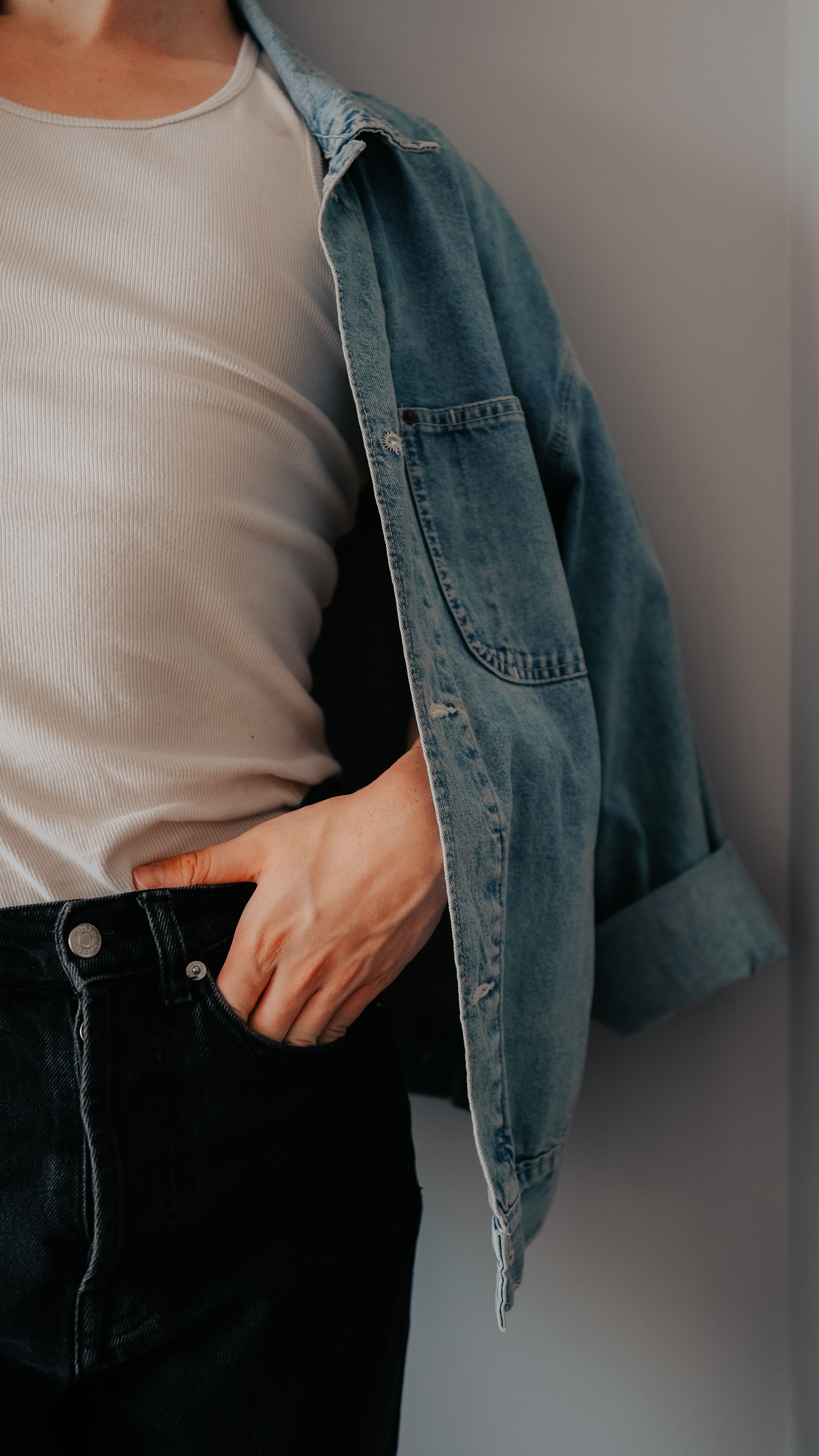 Stylish close-up of a person in denim jacket and white shirt for modern fashion vibe.
