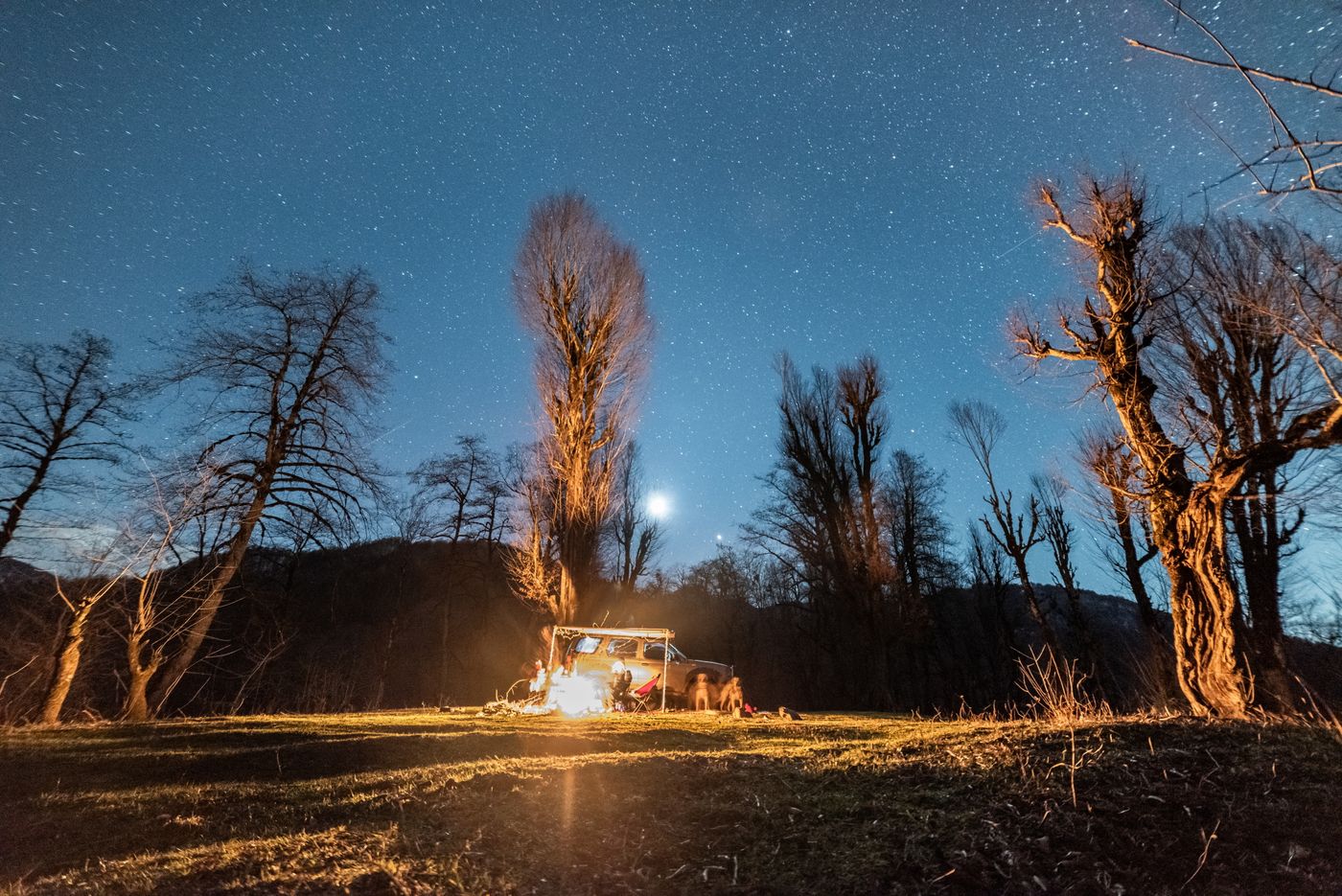 Campers gathered around a warm fire beneath the night sky
