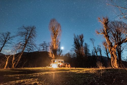 Free Cozy campsite under a starry sky with a warm bonfire illuminating the night. Stock Photo