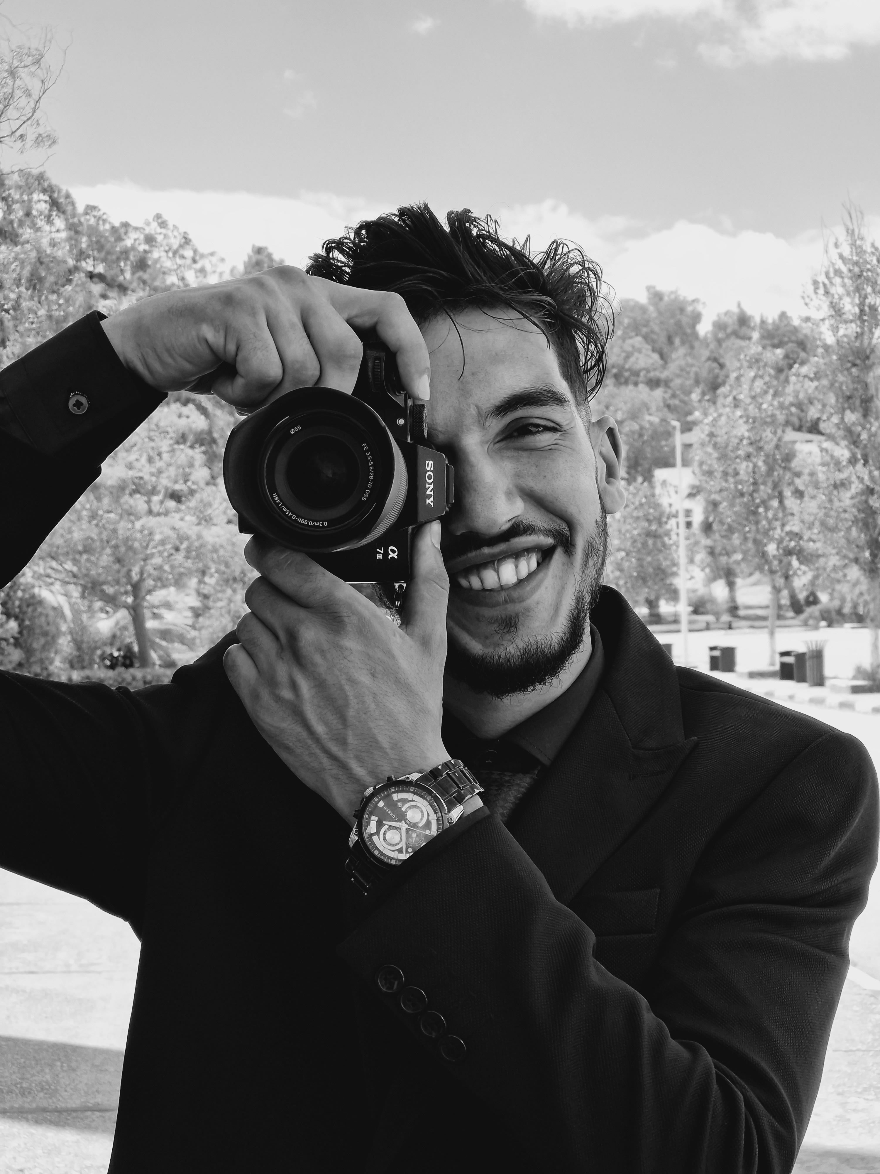 Portrait of a smiling man holding a camera outdoors in Annaba, Algeria.