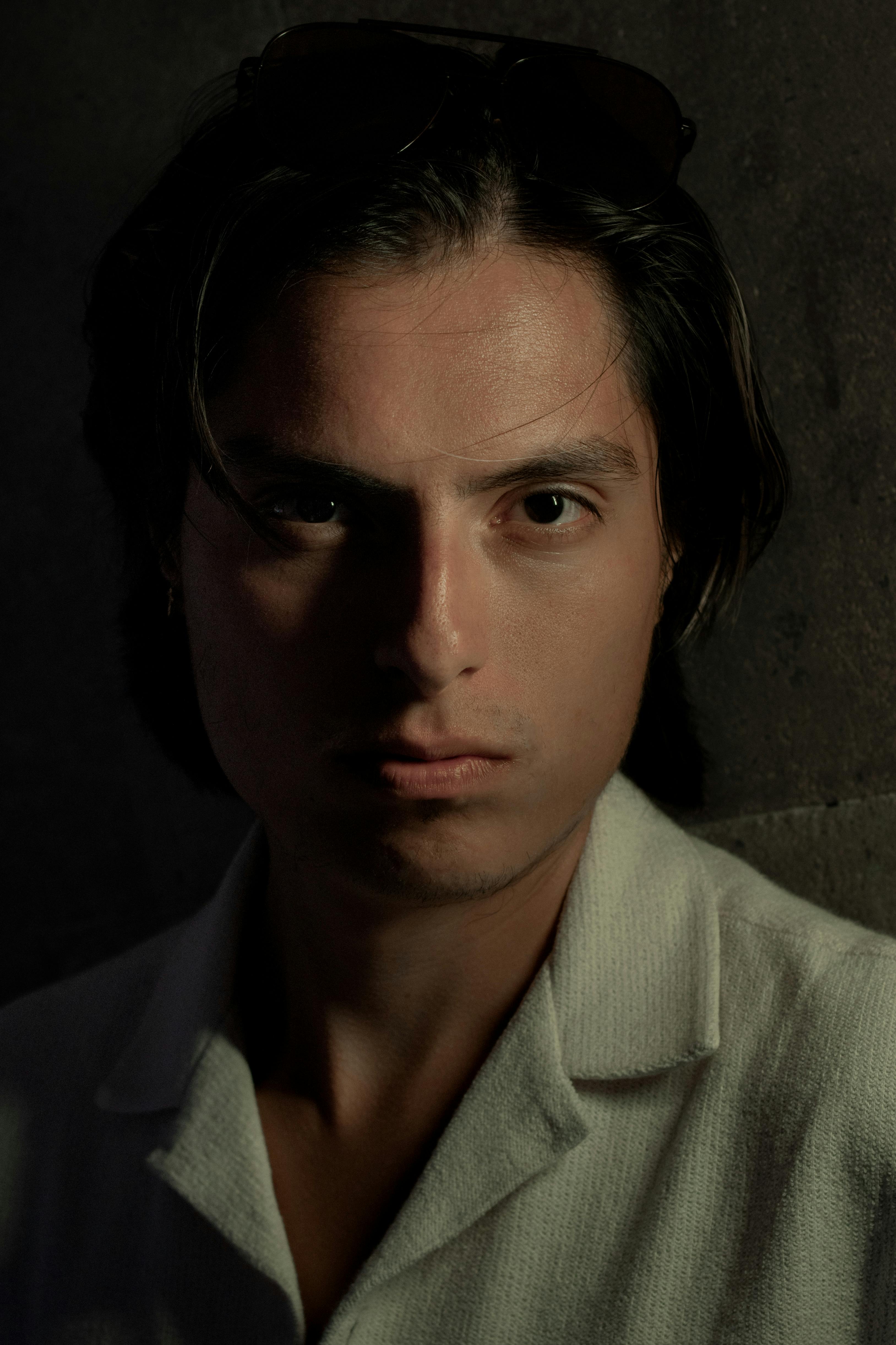 Dramatic portrait of a man with intense gaze, captured in low light, offering a mysterious mood.