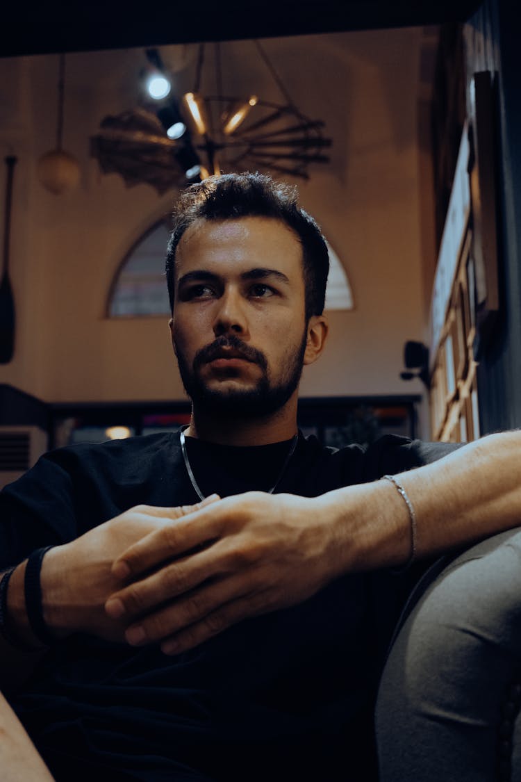 Photo Of A Man Sitting Under Lights 