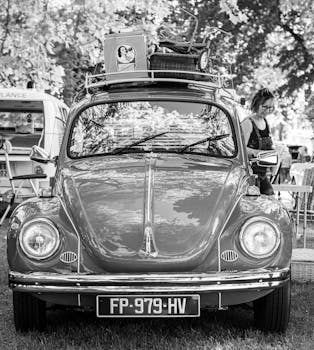 Black and white photo of a classic Volkswagen Beetle with vintage items on the roof.