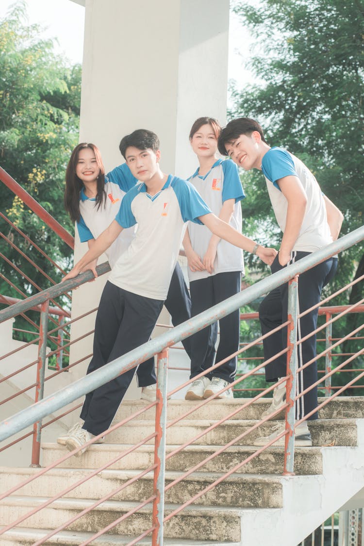 Group Of School Students In Uniform T-Shirts Posing On Stairs