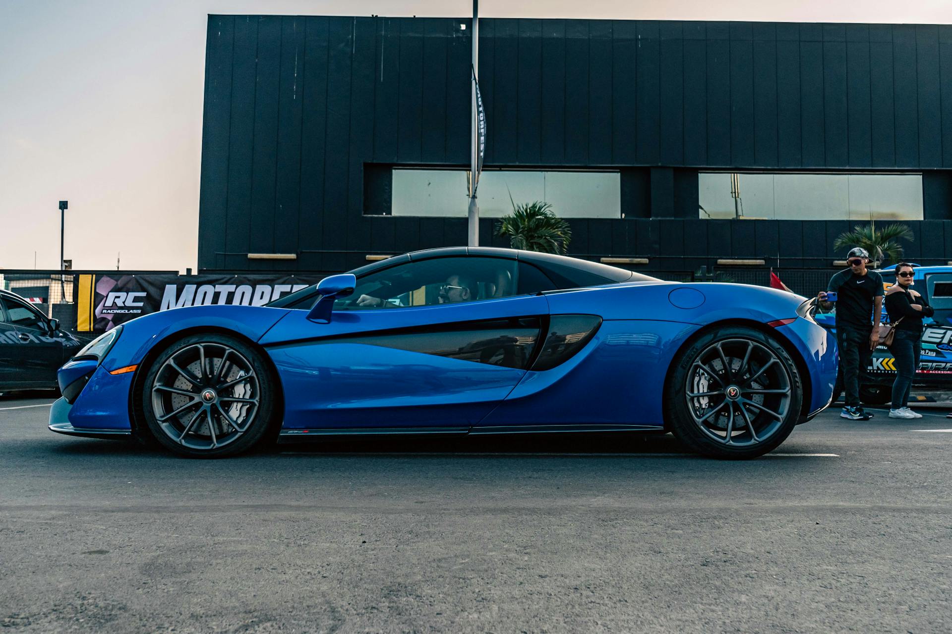 A vibrant sapphire blue sports car parked on a city street during the day.