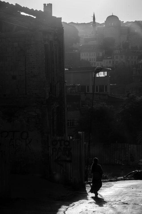 Free A solitary silhouette walks through an urban street, framed by city architecture in monochrome. Stock Photo