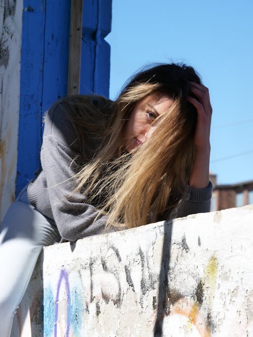 Young Woman with Her Face Covered by Hair Lying in the Window of Abandoned Building