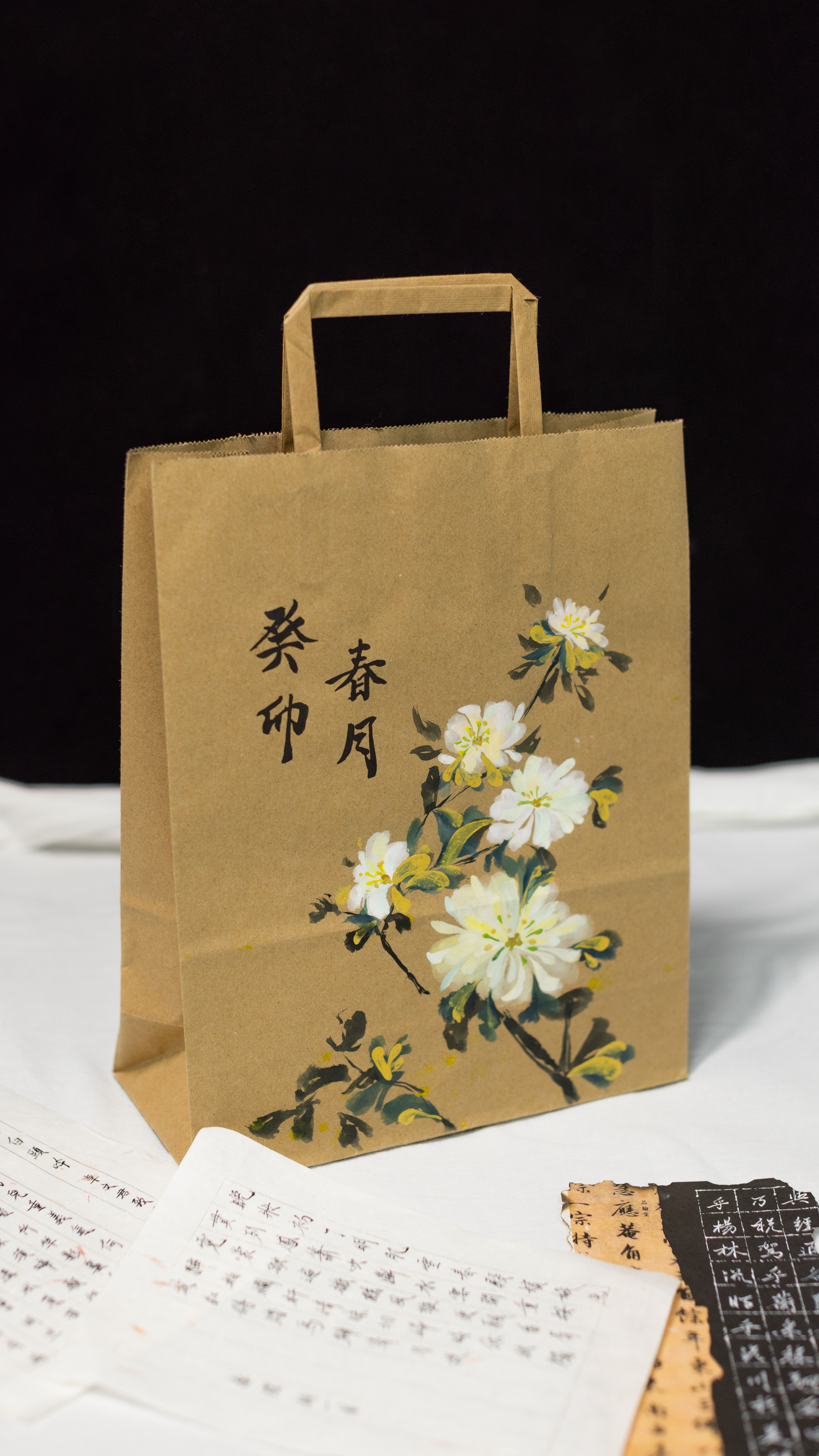 Brown paper bag with floral artwork and Chinese calligraphy, shot indoors.