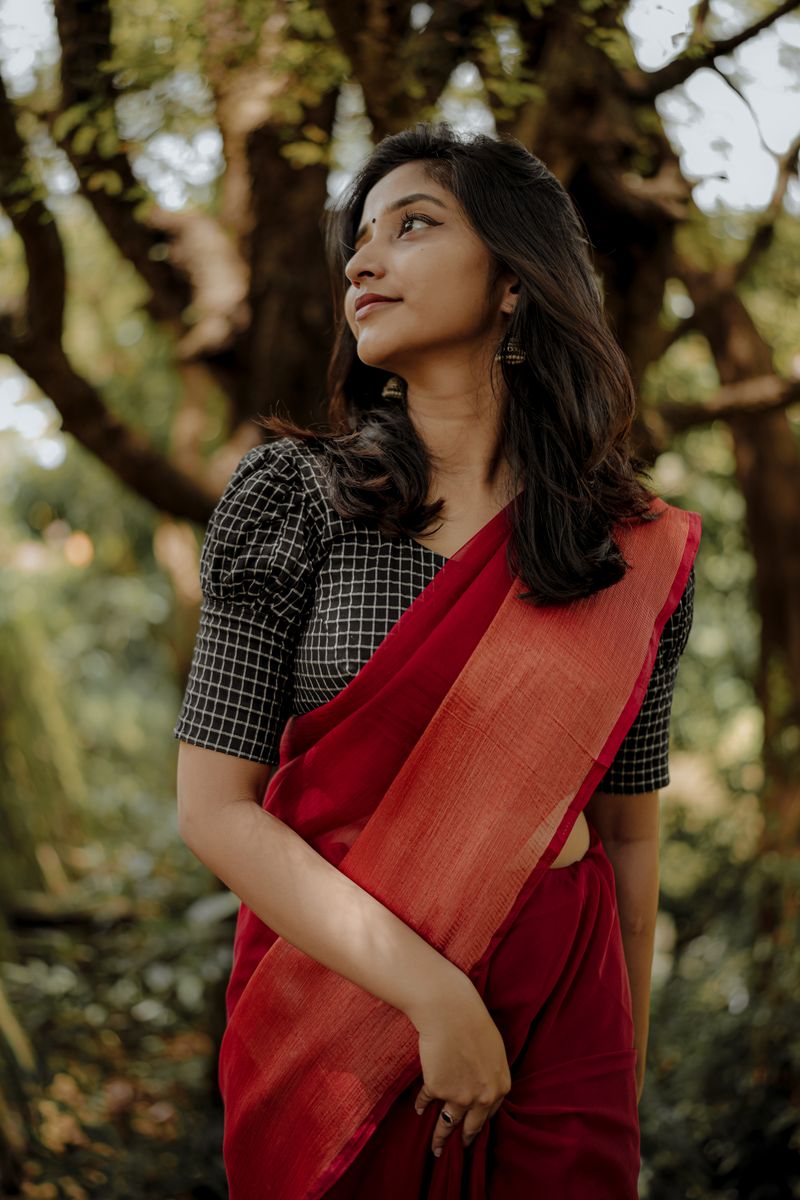 Young woman in a red saree standing amid greenery